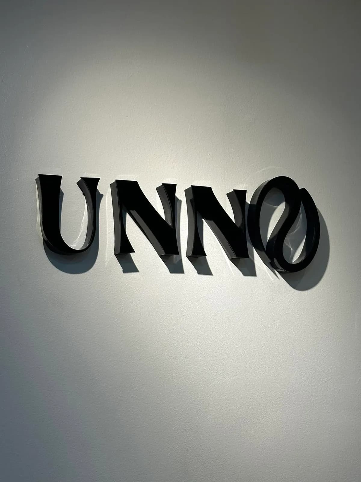 The Unno 3D logo on a white café wall